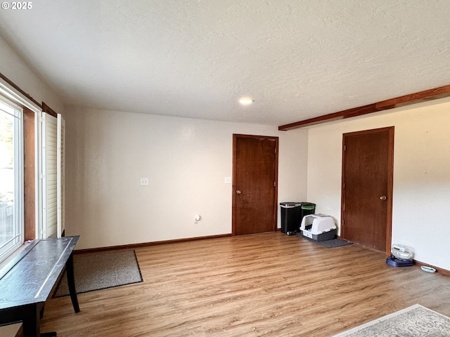 empty room with baseboards, a textured ceiling, and light wood-style flooring