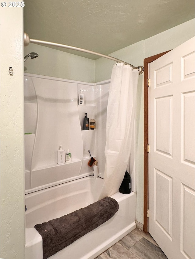 full bath featuring shower / tub combo, a textured wall, and a textured ceiling