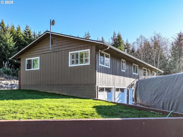 view of side of home featuring an attached garage and a lawn