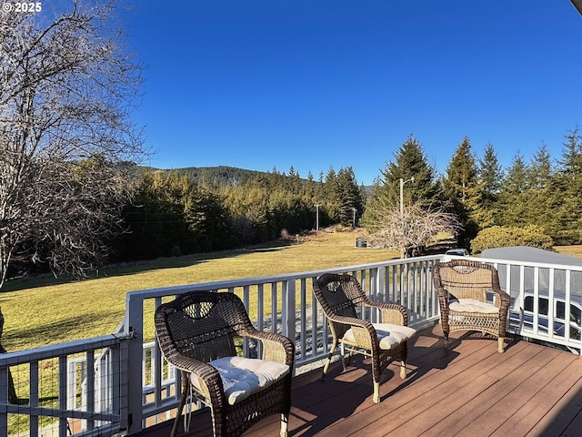 wooden deck featuring a lawn and a forest view