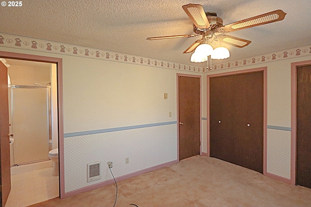 825 Seabreeze Ter, Coos Bay, OR 97420 - unfurnished bedroom featuring wainscoting, two closets, carpet, connected bathroom, and a textured ceiling