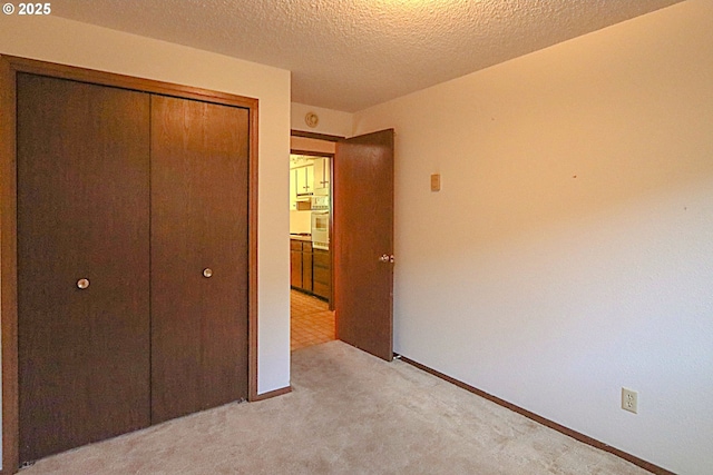 825 Seabreeze Ter, Coos Bay, OR 97420 - unfurnished bedroom with light carpet, a closet, and a textured ceiling