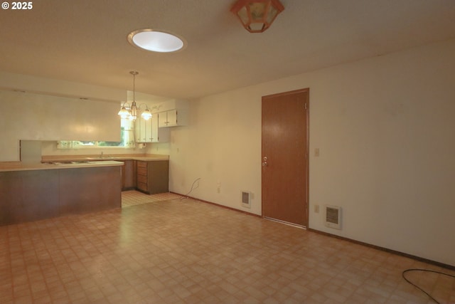 825 Seabreeze Ter, Coos Bay, OR 97420 - kitchen with light flooring, a chandelier, pendant lighting, a peninsula, and light countertops