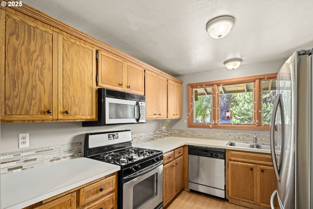 2301 SW 22nd St, Troutdale, OR 97060 - kitchen featuring stainless steel appliances, decorative backsplash, light countertops, a textured ceiling, and light wood finished floors