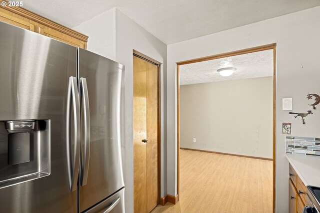 2301 SW 22nd St, Troutdale, OR 97060 - kitchen with stainless steel appliances, light wood finished floors, light countertops, brown cabinetry, and a textured ceiling