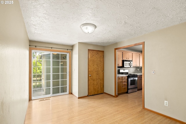 2301 SW 22nd St, Troutdale, OR 97060 - kitchen with stainless steel appliances, light wood-style floors, a textured ceiling, and brown cabinets
