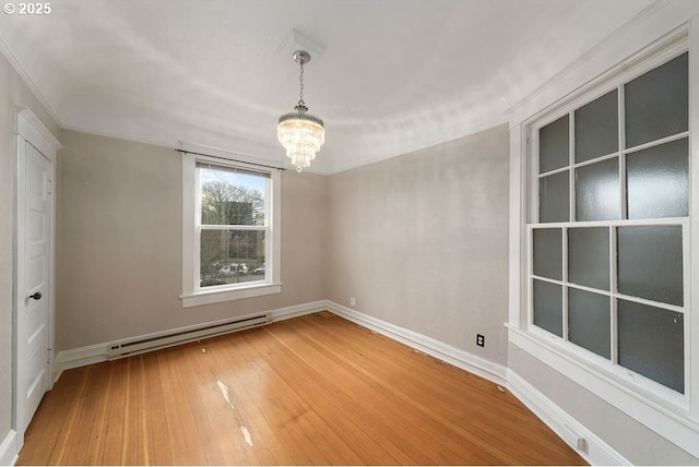 empty room with hardwood / wood-style floors, a notable chandelier, and baseboard heating