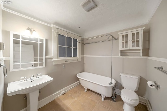 bathroom with a bathing tub, sink, toilet, and a textured ceiling