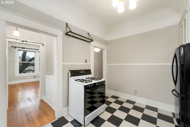 kitchen with black refrigerator, white cabinetry, and white gas range oven