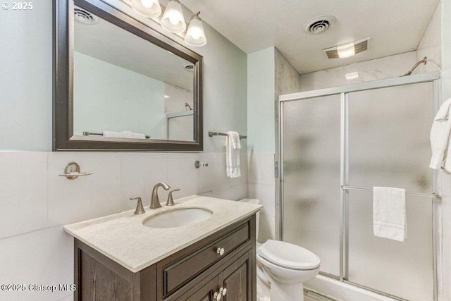 full bathroom featuring vanity, tile walls, visible vents, and a stall shower