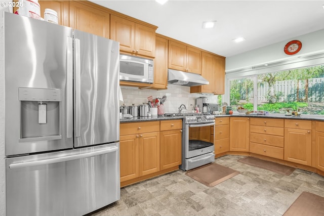 10145 SW Paulina Dr, Tualatin, OR 97062 - kitchen with under cabinet range hood, decorative backsplash, dark stone counters, and appliances with stainless steel finishes
