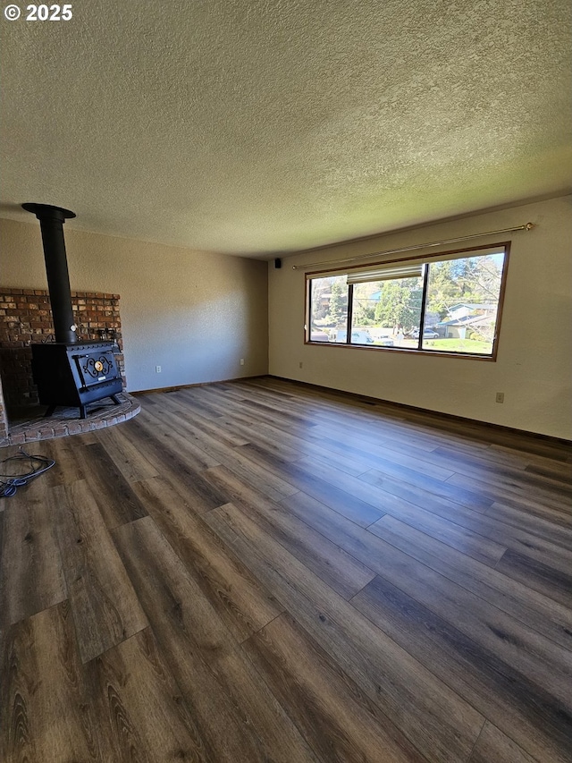 unfurnished living room featuring baseboards, a textured ceiling, dark wood-style flooring, and a wood stove