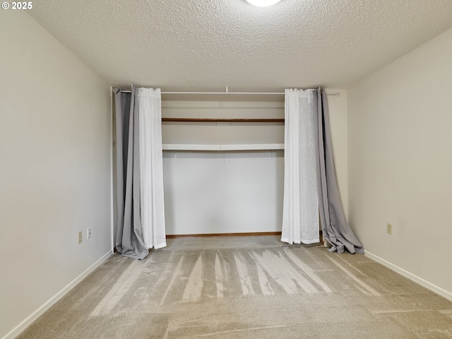 unfurnished bedroom featuring carpet, a textured ceiling, baseboards, and a closet