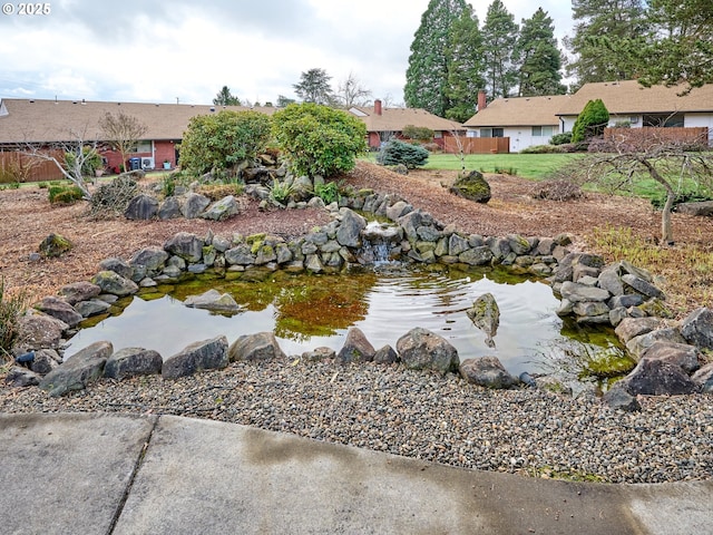 exterior space with a small pond and fence