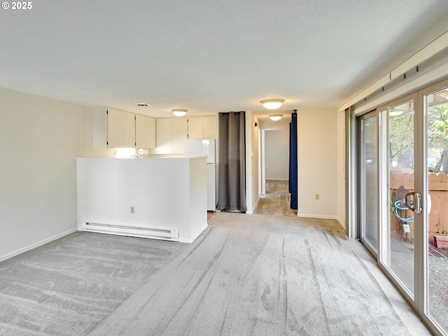 unfurnished room with a baseboard heating unit, light carpet, a textured ceiling, and baseboards