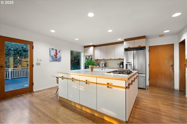 kitchen featuring light wood finished floors, recessed lighting, stainless steel appliances, white cabinets, and light countertops