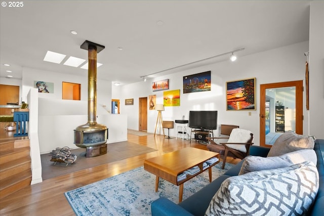 living area with track lighting, a wood stove, recessed lighting, and wood finished floors