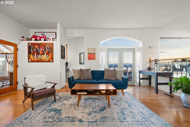 living area with a wealth of natural light, visible vents, french doors, and wood finished floors