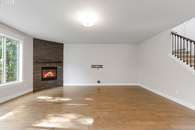 28340 SW Mcgraw Ave, Wilsonville, OR 97070 - unfurnished living room featuring stairway, wood finished floors, a stone fireplace, and baseboards