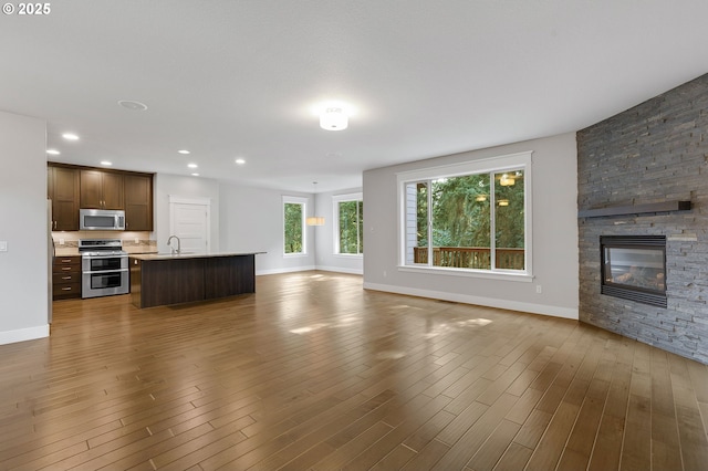 unfurnished living room featuring a fireplace, wood-type flooring, and sink