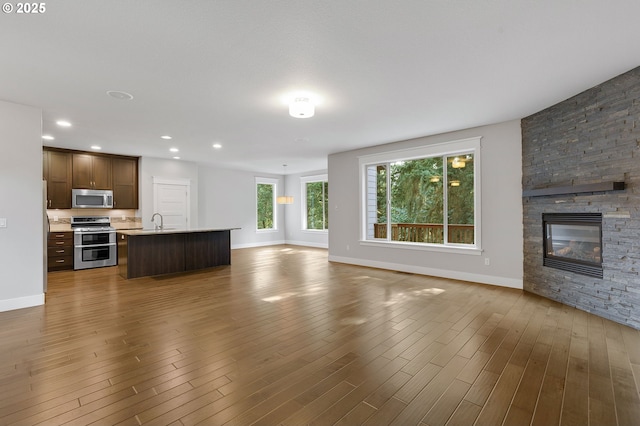 28340 SW Mcgraw Ave, Wilsonville, OR 97070 - unfurnished living room with a sink, baseboards, dark wood-style floors, a stone fireplace, and recessed lighting
