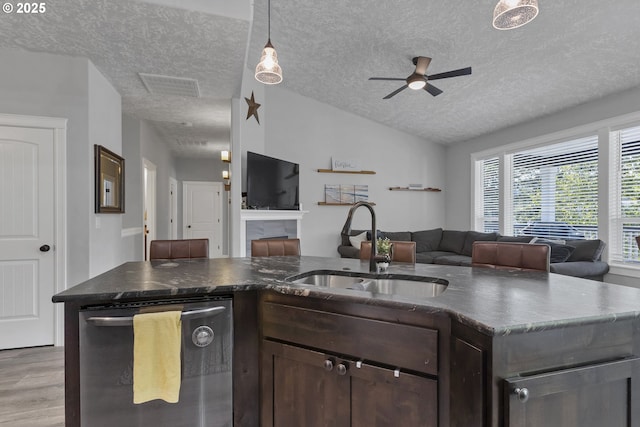 kitchen featuring a sink, dark brown cabinets, open floor plan, and stainless steel dishwasher