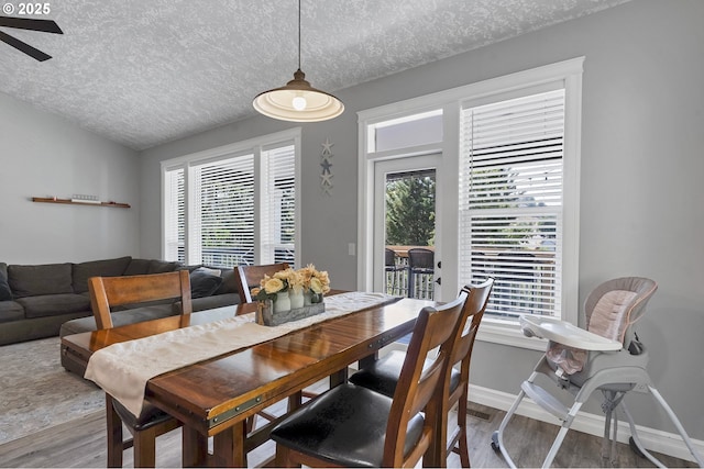 dining area with a wealth of natural light, lofted ceiling, a textured ceiling, and wood finished floors