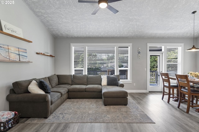 living area featuring baseboards, wood finished floors, a textured ceiling, and ceiling fan