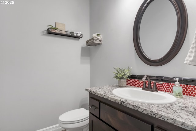 bathroom featuring decorative backsplash, baseboards, toilet, and vanity