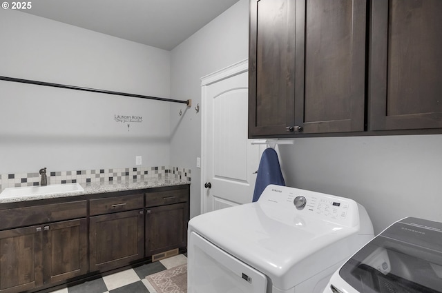 clothes washing area featuring separate washer and dryer, cabinet space, light floors, and a sink