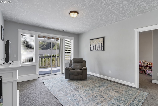 sitting room with carpet, baseboards, and a textured ceiling