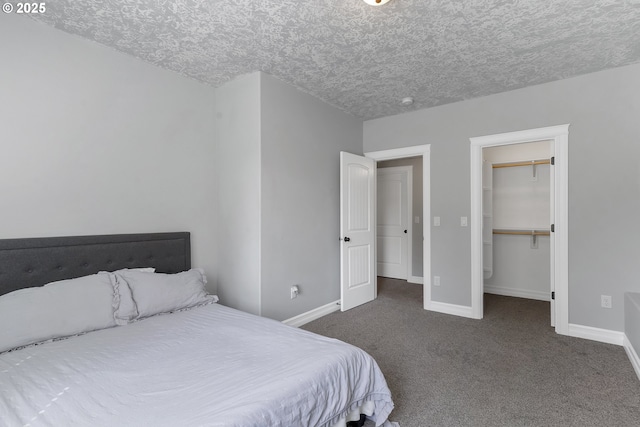 carpeted bedroom with a walk in closet, baseboards, and a textured ceiling