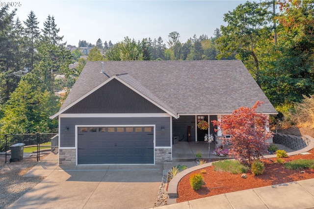 view of front of home with stone siding, an attached garage, concrete driveway, and fence