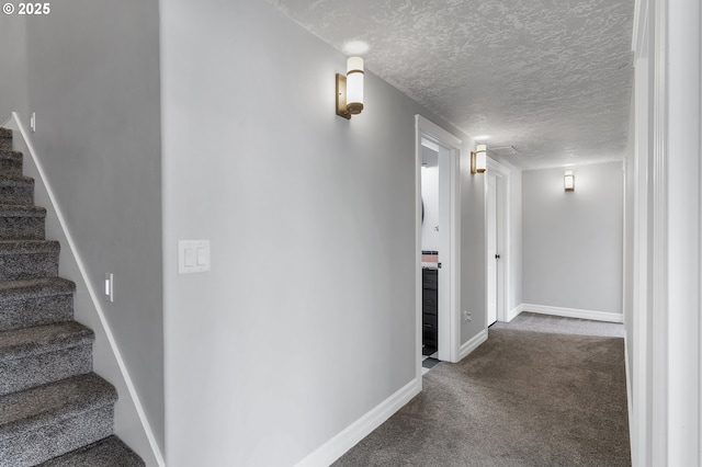 hallway featuring baseboards, carpet floors, a textured ceiling, and stairs