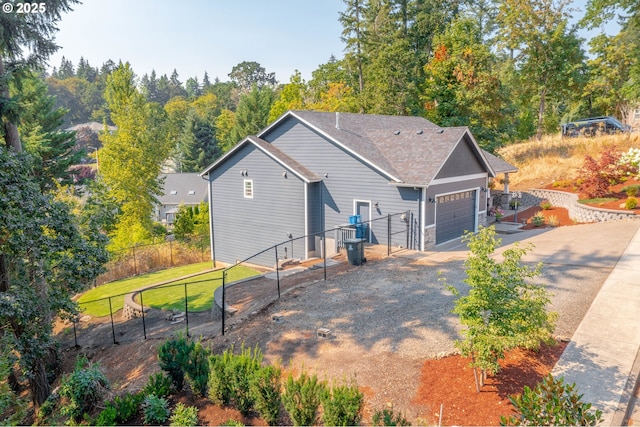 rear view of house with an attached garage, fence, a yard, and driveway