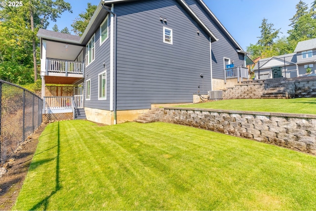 rear view of house featuring a yard, a balcony, central AC unit, and fence