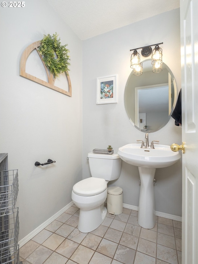 half bathroom with tile patterned flooring, toilet, and baseboards