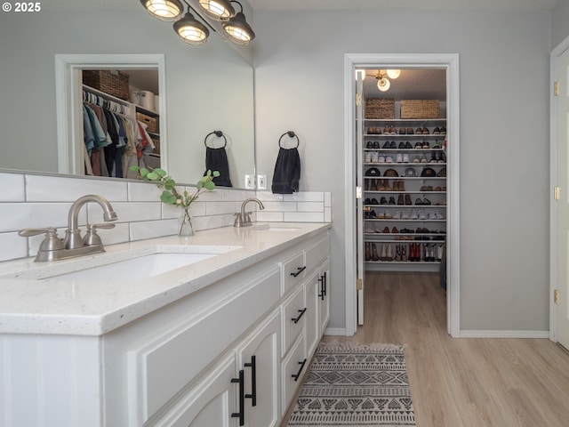 full bath with tasteful backsplash, wood finished floors, a sink, and double vanity