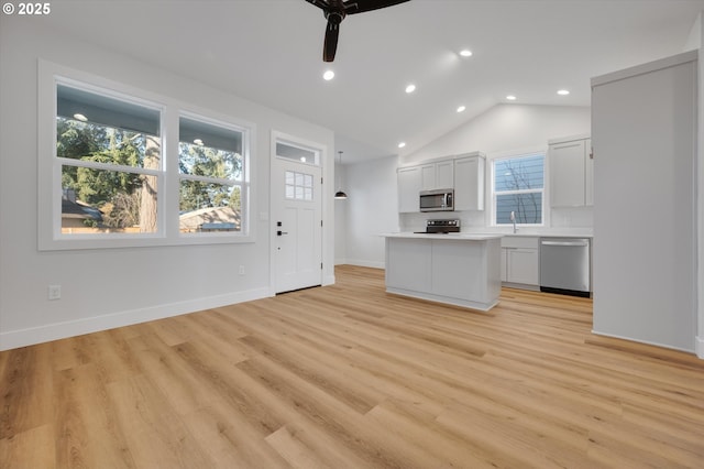 kitchen with lofted ceiling, light hardwood / wood-style floors, white cabinets, and appliances with stainless steel finishes