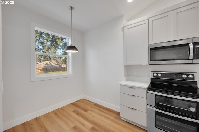 kitchen featuring white cabinetry, appliances with stainless steel finishes, pendant lighting, and light hardwood / wood-style floors