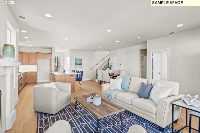 8276 SE Orion Ln, Hillsboro, OR 97123 - living room featuring stairs, light wood finished floors, recessed lighting, baseboards, and a fireplace