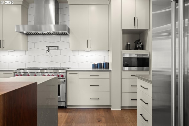 4480 Upper Dr, Lake Oswego, OR 97035 - kitchen featuring high end appliances, wall chimney range hood, dark wood-type flooring, tasteful backsplash, and modern cabinets