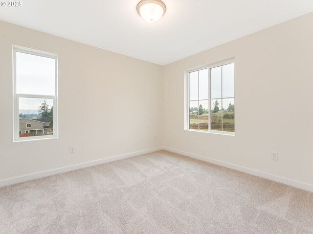 spare room with light colored carpet and baseboards