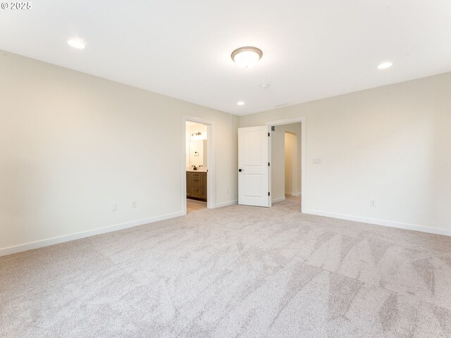 unfurnished bedroom featuring recessed lighting, baseboards, ensuite bathroom, and light carpet