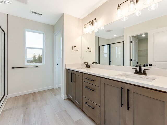 bathroom with visible vents, a sink, a shower stall, and double vanity