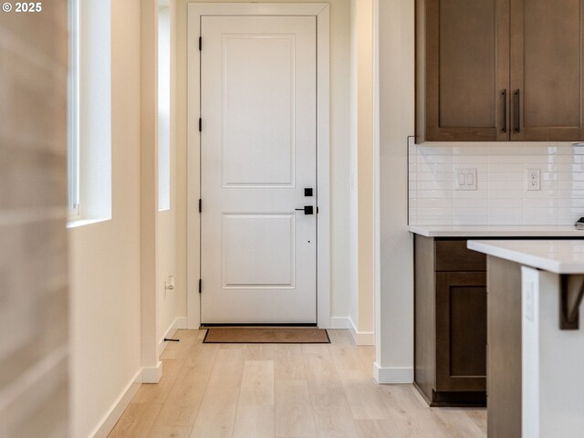 doorway with baseboards and light wood-style flooring