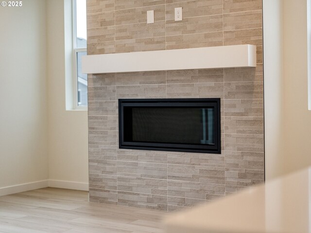 details with a tiled fireplace, baseboards, and wood finished floors