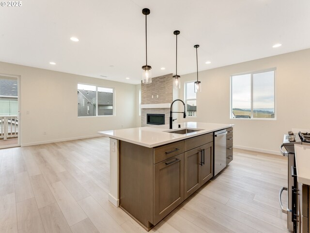 kitchen featuring a sink, open floor plan, light wood-style flooring, stainless steel appliances, and light countertops