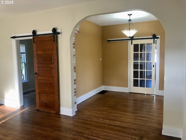 3929 SE 65th Ave, Portland, OR 97206 - spare room with a barn door, arched walkways, and dark wood-type flooring