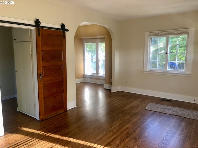 3929 SE 65th Ave, Portland, OR 97206 - spare room featuring arched walkways, dark wood-type flooring, and a barn door